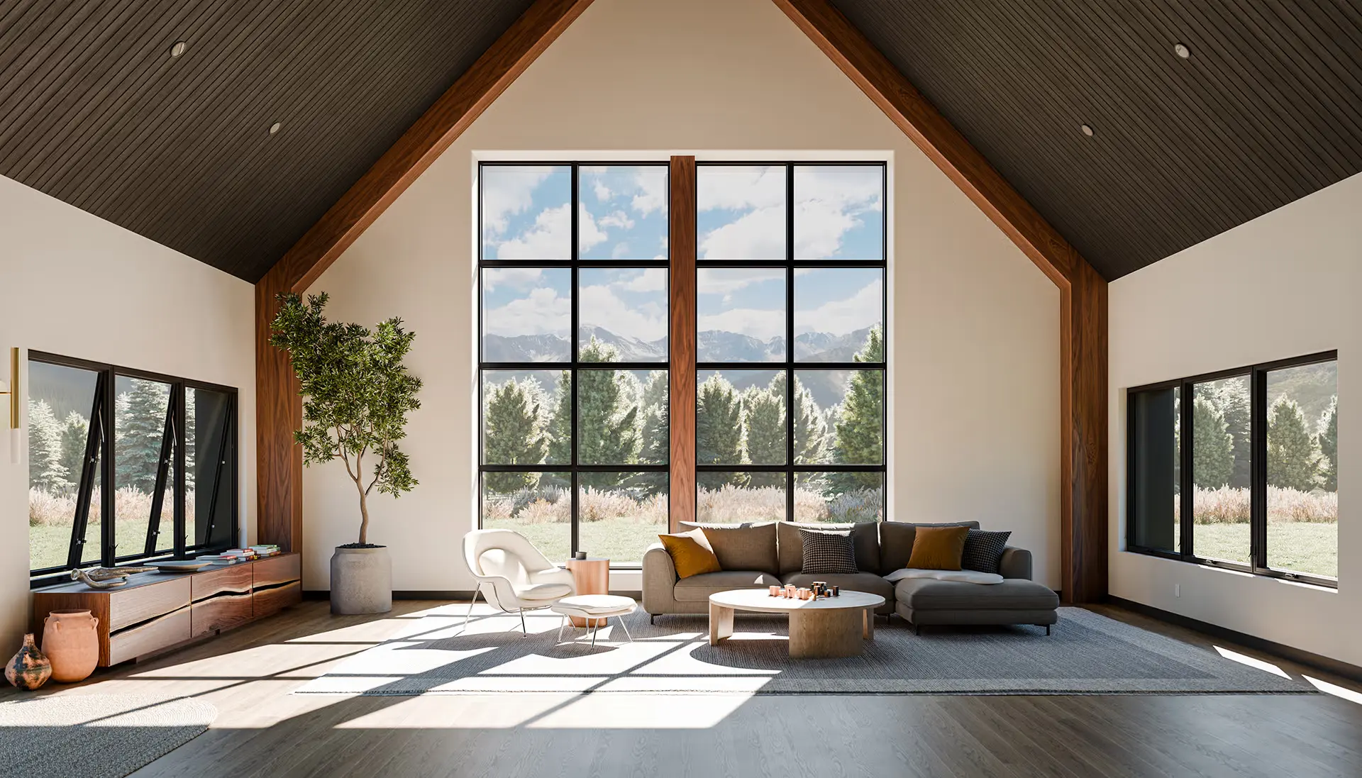 A spacious, modern living room with high vaulted ceilings, large grid windows showing a scenic view of trees and mountains, contemporary furniture, a potted tree, and neutral, earthy tones throughout.