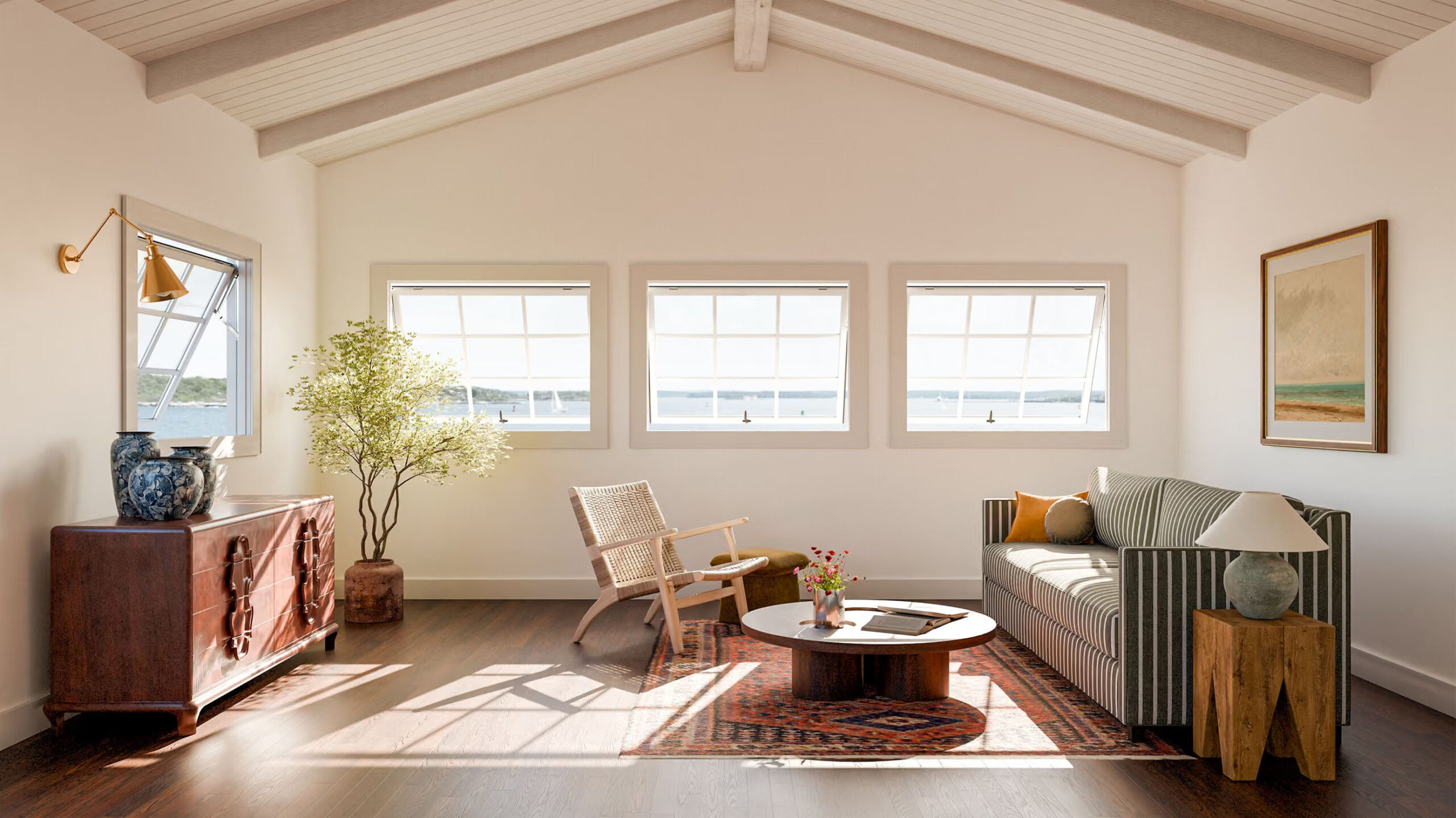 marvin_awning_pushout_window Sunlit living room with three windows, a sofa, a wooden chair, a round coffee table on a rug, a sideboard with vases, a plant, and wall art. White walls and ceiling with exposed beams create an airy feel.